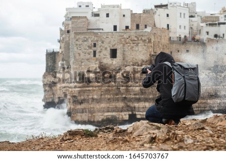 Photographer taking picture of a stormy sea in Polignano a Mare, Italy