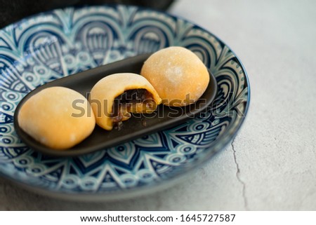 Yellow-colored Japanese Mochi in rice dough and on a pattern blue plate background. Traditional Japanese dessert.
