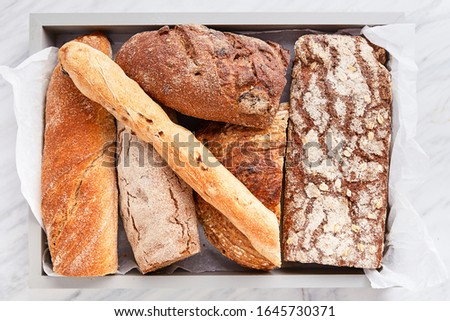 Breads variety on a marble background viewed from above. Various whole grain breads selection. Top view
