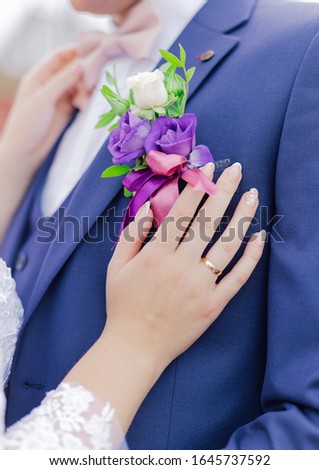 Young bride adjusts the boutonniere to the groom.