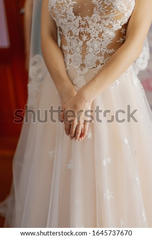 Young bride hands on a wedding dress.