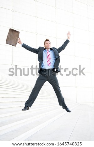 Excited businessman jumping on a set of white marble steps