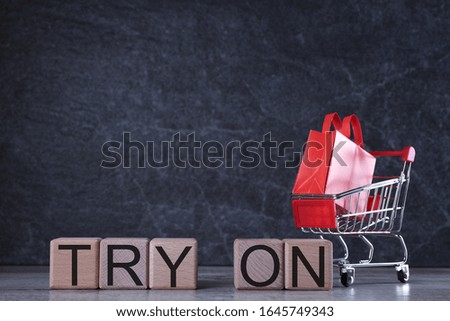 Shopping concept. Wooden cubes with word try on  on the dark background with shopping basket