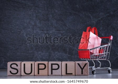 Shopping concept. Wooden cubes with word supply on the dark background with shopping basket