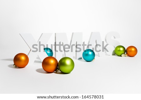 3D In capital letter Xmas written on white background with christmas balls