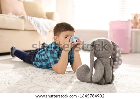 Little photographer taking picture of toy bunny at home