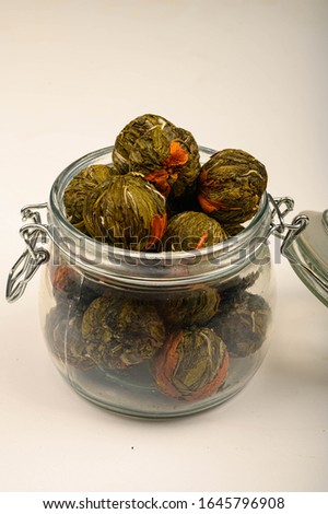 A ball of flower tea in a glass jar on a white background. Close up.