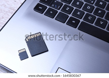 Micro SD memory card adapter on laptop background on the wooden table. close up front view