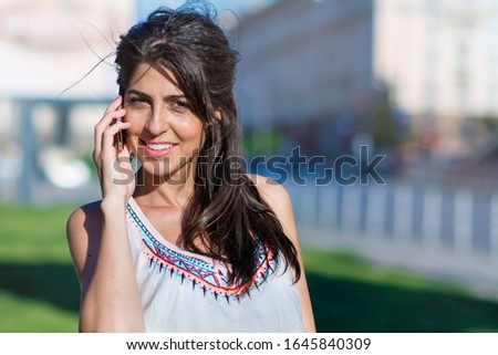 Portrait of Beautiful Smiling  Woman Talking on the Phone Outdoor 