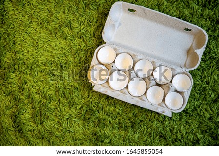 10 broken empty egg shells lie in a box on artificial grass. top view, close-up, place for copyspace