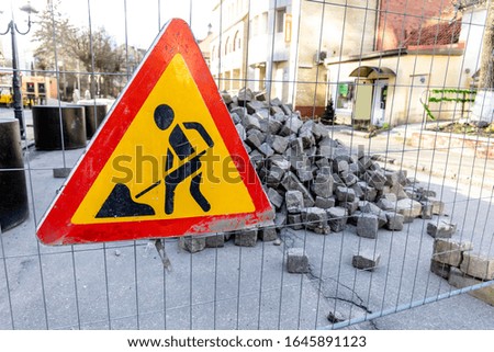 road sign repair work on the background of a pile of stones on the street