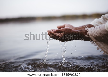 A closeup shot of a person wearing a biblical robe drinking water with hands Royalty-Free Stock Photo #1645903822
