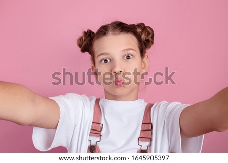 happy young girl having fun and taking a selfie over pink background