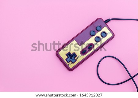 Retro computer gaming controller on a pink background