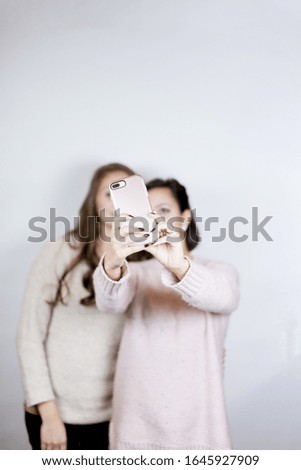 A vertical shot of females taking a selfie with a smartphone