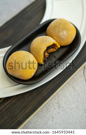 Yellow-colored Japanese Mochi in rice dough and on wooden background. Traditional Japanese dessert.