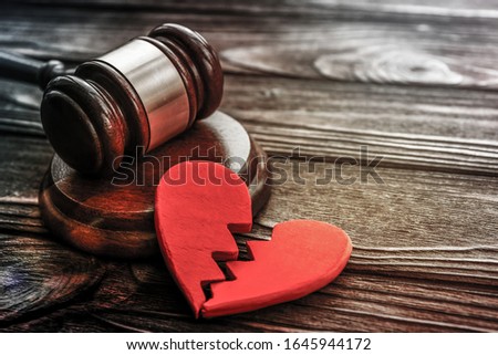 judge's hammer, two halves of heart on wooden background. divorce, conflict, family law.