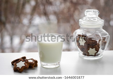 Tasty breakfast or snack. A glass of fresh organic milk with biscuits in a star shape on winter window view. Copy space
