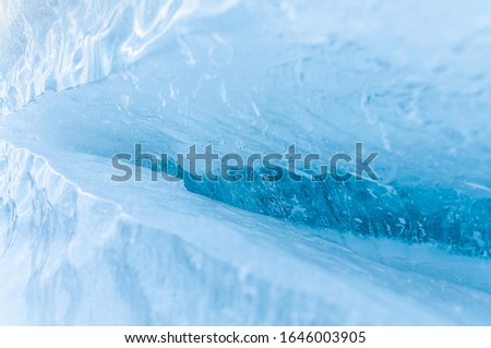 Close up of blue ice. Crack in thick solid layer of ice. Nature background photo, frozen ice image.