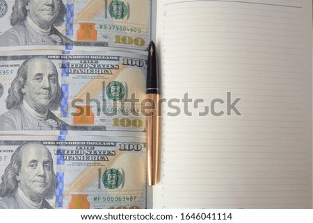 dollars banknotes in a diary, a book with money and a golden pen