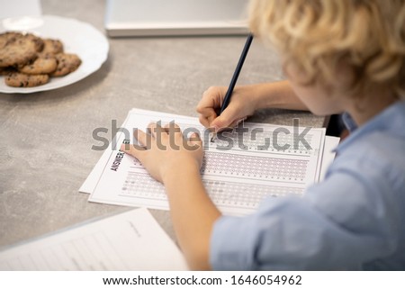 Test. Close uo picture of a blond boy wrtiting a test