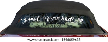 Old-fashioned JUST MARRIED message written on car's rear window.