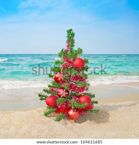 Christmas tree with red decorations on the sea beach. Christmas vacation concept.