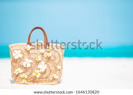 Beach accessories - straw bag and coconut on white beach