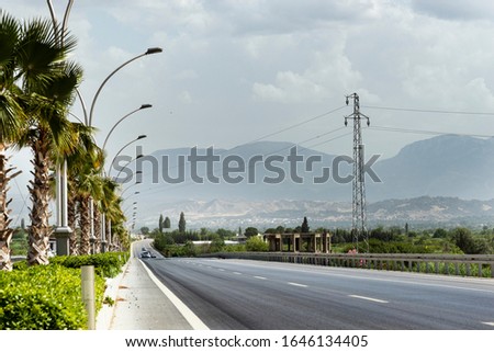 Straight road background with cloudy sky and highway lamps.