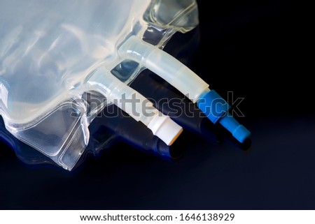 IV bag with medication ports and IV tubing on dark blue. Royalty-Free Stock Photo #1646138929
