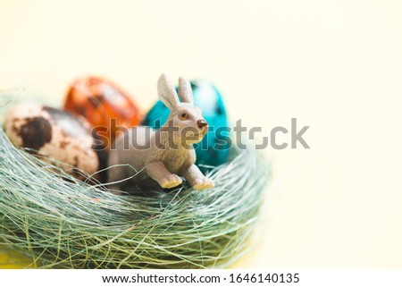 Easter rabbits toy, eggs in nest of twigs and row of hanging eggs in soft light on vintage background. Easter mood decoration. Funny Easter concept.