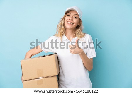 Young delivery woman isolated on blue background giving a thumbs up gesture