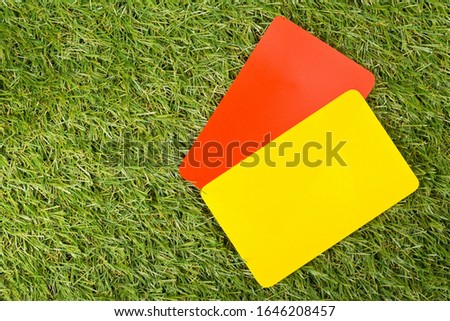 Soccer sports referee yellow and red cards on grass background - penalty, foul or sports concept, top view flat lay from above