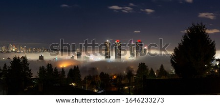 Burnaby, Vancouver, British Columbia, Canada. Beautiful Panoramic Aerial View of a modern city during a fog covered night before winter morning sunrise.
