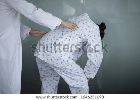 Doctor checking patient's backache in office
