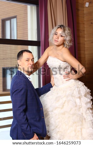 Happy Newlyweds pose against the background of a window.