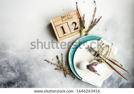 Festive table setting for holiday Easter dinner decorated with eggs and heather flowers on stone background with copy space