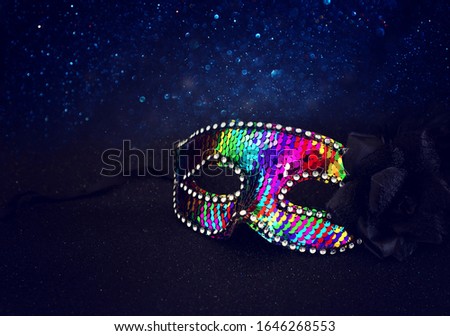 Photo of elegant and delicate colorful sequins Venetian mask over dark glitter background