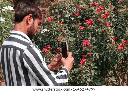 man tourist taking photo on beautiful view of flowers garden  with mobile smart phone camera,mobile photography with smart phone,macro photography with phone camera,male makes a photo on your phone. 