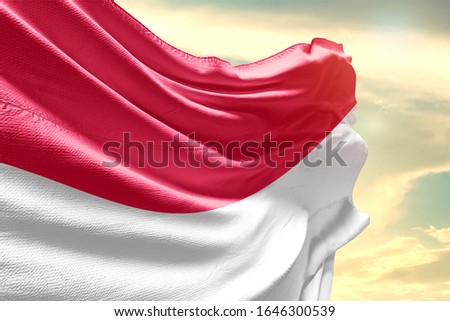 Waving Flag of Indonesia in Blue Sky. Indonesia Flag on pole for Independence day. The symbol of the state on wavy cotton fabric.
