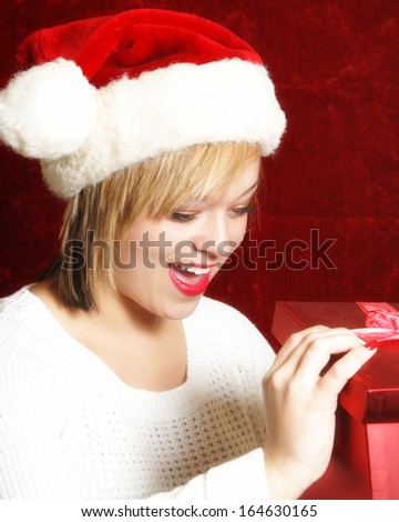 An attractive young woman opens a gift on Christmas.