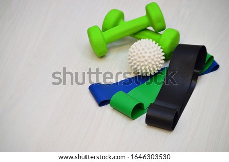 Sports equipment for a healthy sports lifestyle. Dumbbells, hand or foot weights, massage ball, elastic bands, bandages, a roll for the press, an expander hoop and others