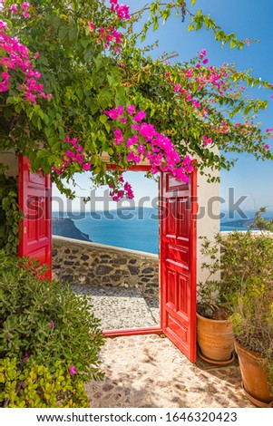 Sea view and architecture in Thira, Santorini, Greece. Beautiful vertical banner for luxury travel and summer vacation. Beautiful pink flowers with red wooden gate over the caldera and wall exterior