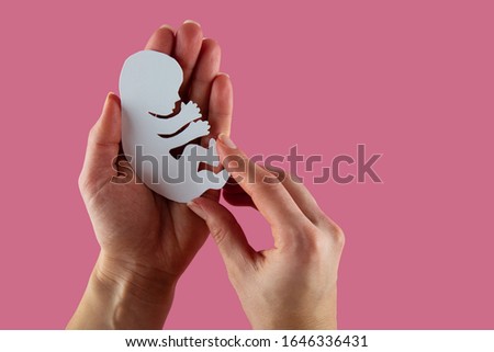 White paper embryo silhouette in woman hands.