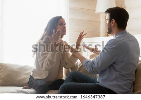 Angry young couple sit on couch in living room having family fight or quarrel suffer from misunderstanding, millennial husband and wife dispute involved in argument, relationships problems concept Royalty-Free Stock Photo #1646347387