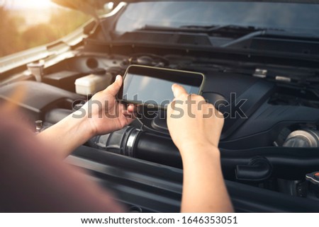 Young woman using mobile phone take a picture of a broken car.