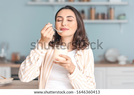 Young woman eating tasty yogurt at home Royalty-Free Stock Photo #1646360413