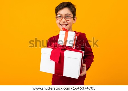 smiling boy in a red jumper with two box of a gift for Valentine's day on a yellow background