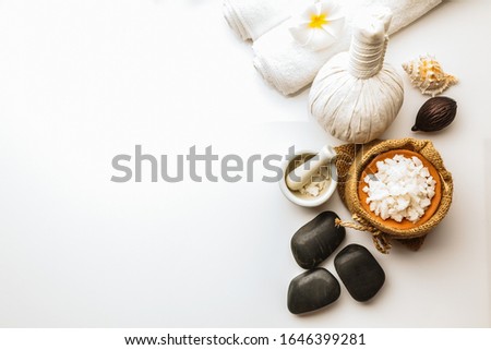 Flat lay, top view Composition of spa treatments with Towels, sea salt , stones and herbal massage ball on white background