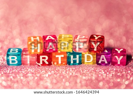 Happy Birthday with colored blocks letters on pink glitter backgrounds. Greeting card to celebrate.